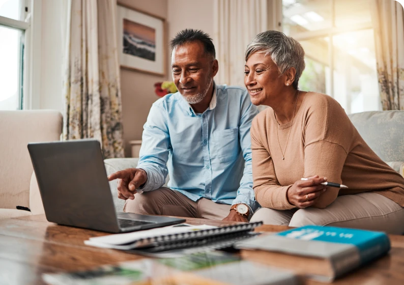 Elderly couple using laptop at home.